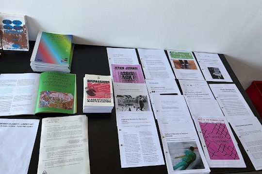 A selection of art worker publications and bulletins spread over a black tablecloth