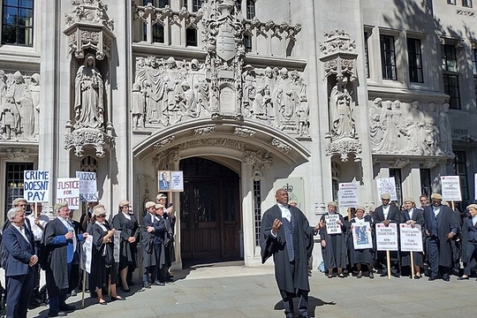 A rally in front of an old building, with posters including 'Crime doesn't pay'. A rally in front of an old building, with posters including 'Crime doesn't pay'.