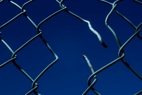 A broken chain-link fence. A broken chain-link fence.